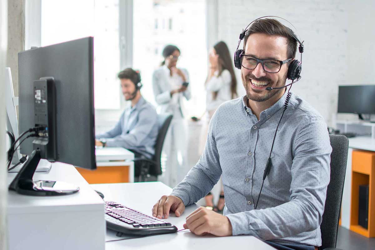 Man seated at a computer and laughing