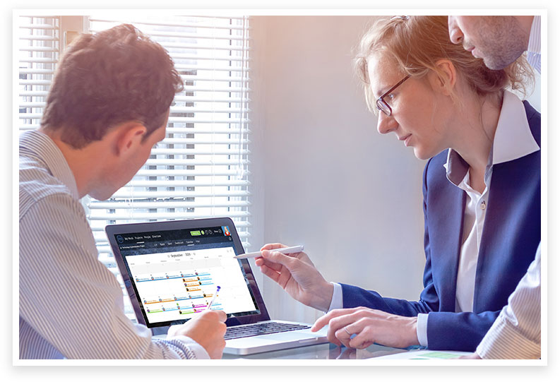 2 men and a woman around a laptop displaying a calendar planning view in ProjectManager.com